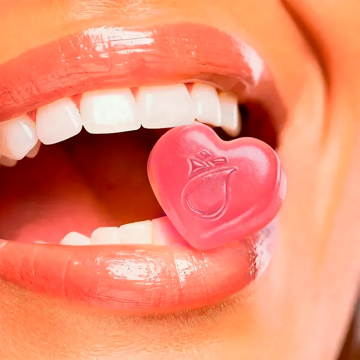 Gominola en forma de corazón rosa en la boca de una mujer, enfocada en bienestar femenino.